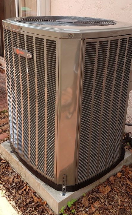 Newly installed Trane outdoor condenser on a concrete pad beside a home